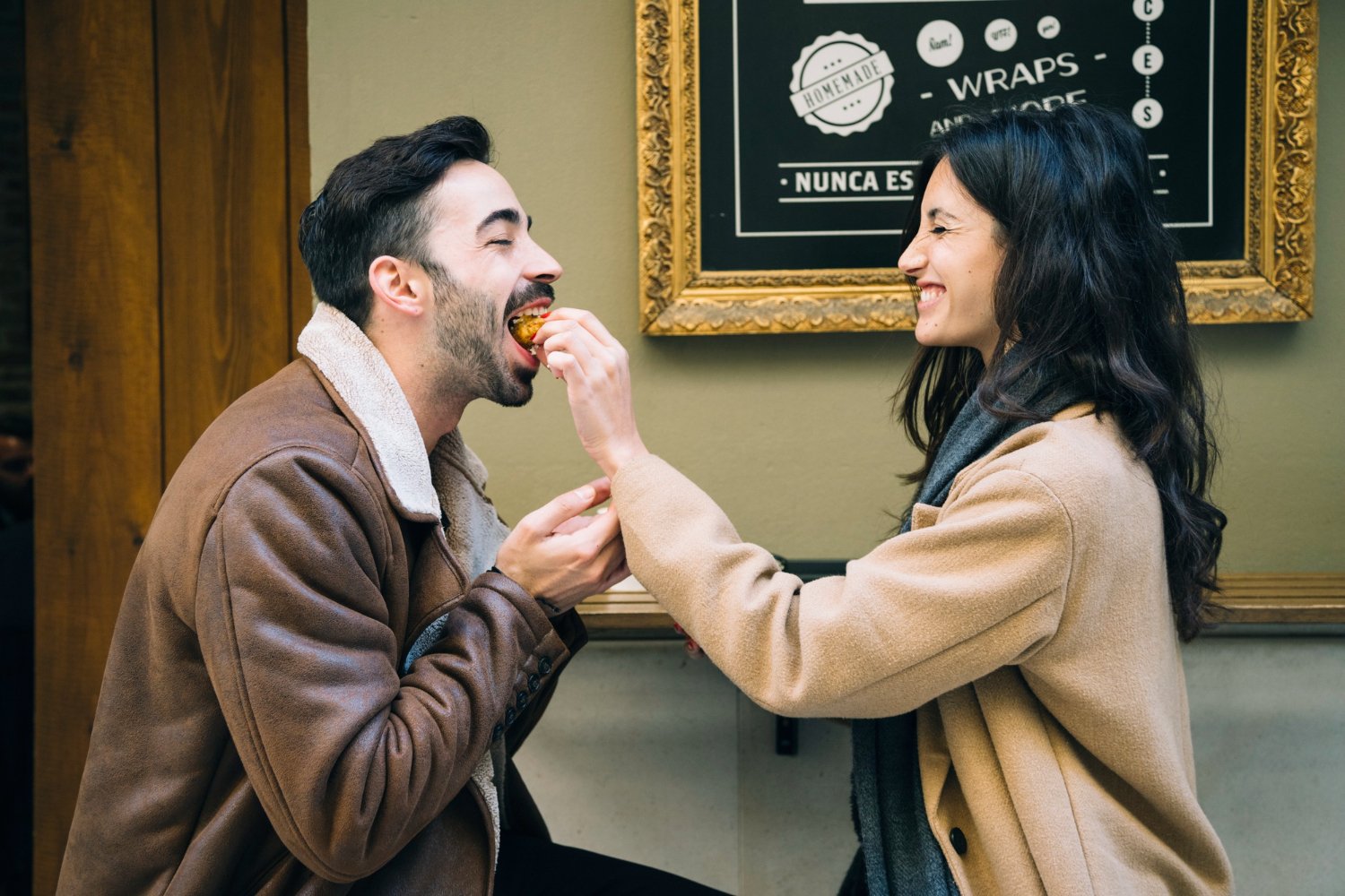 A couple sharing a playful conversation at a neighborhood café