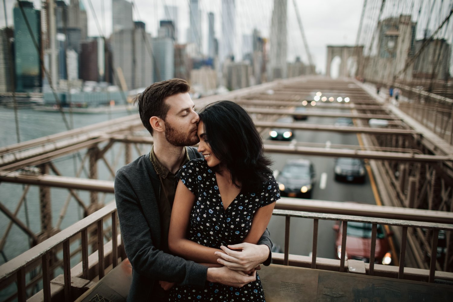 Couple sharing a quiet moment on the Brooklyn Bridge above New York traffic