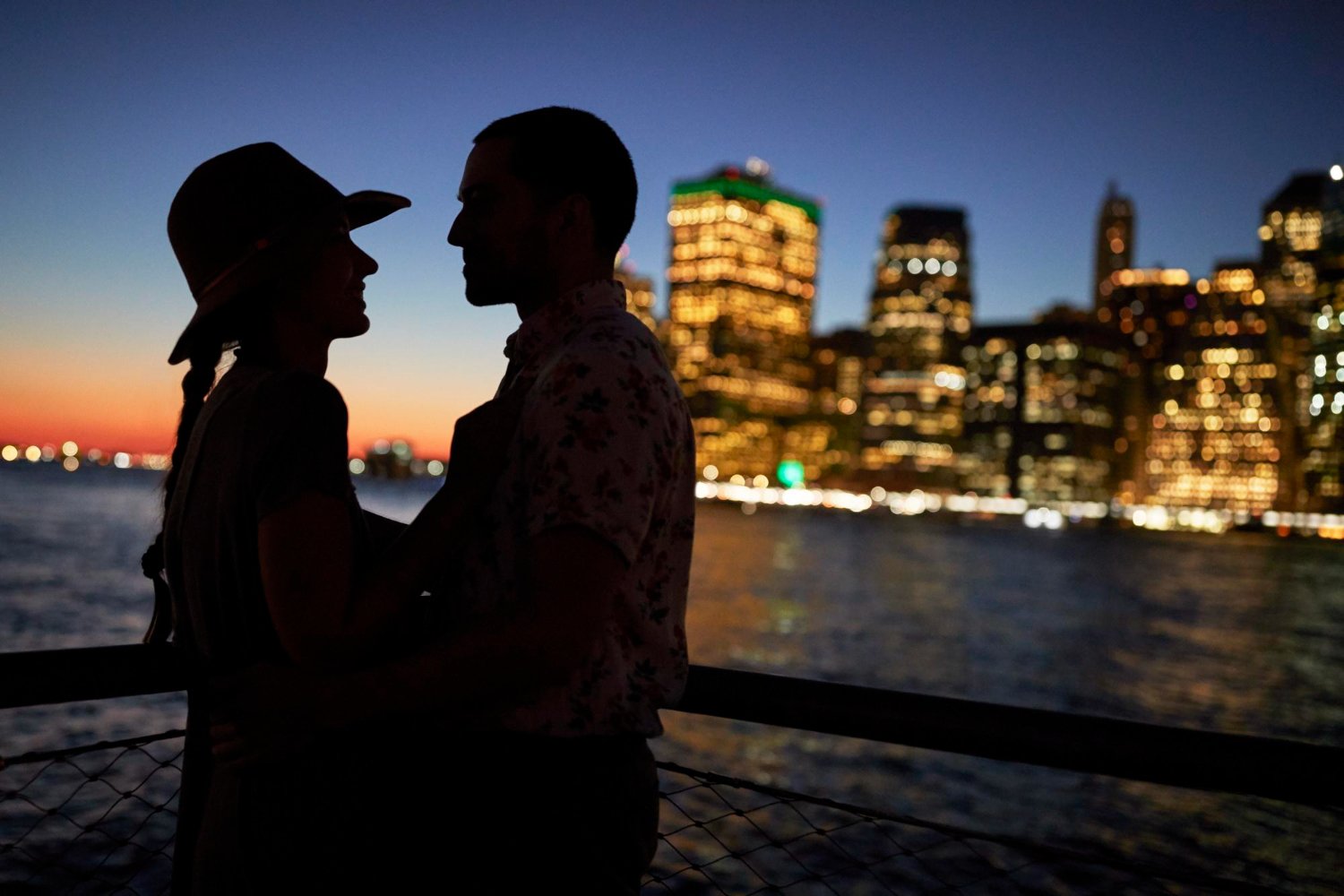 A couple silhouetted together against the New York City skyline at sunset